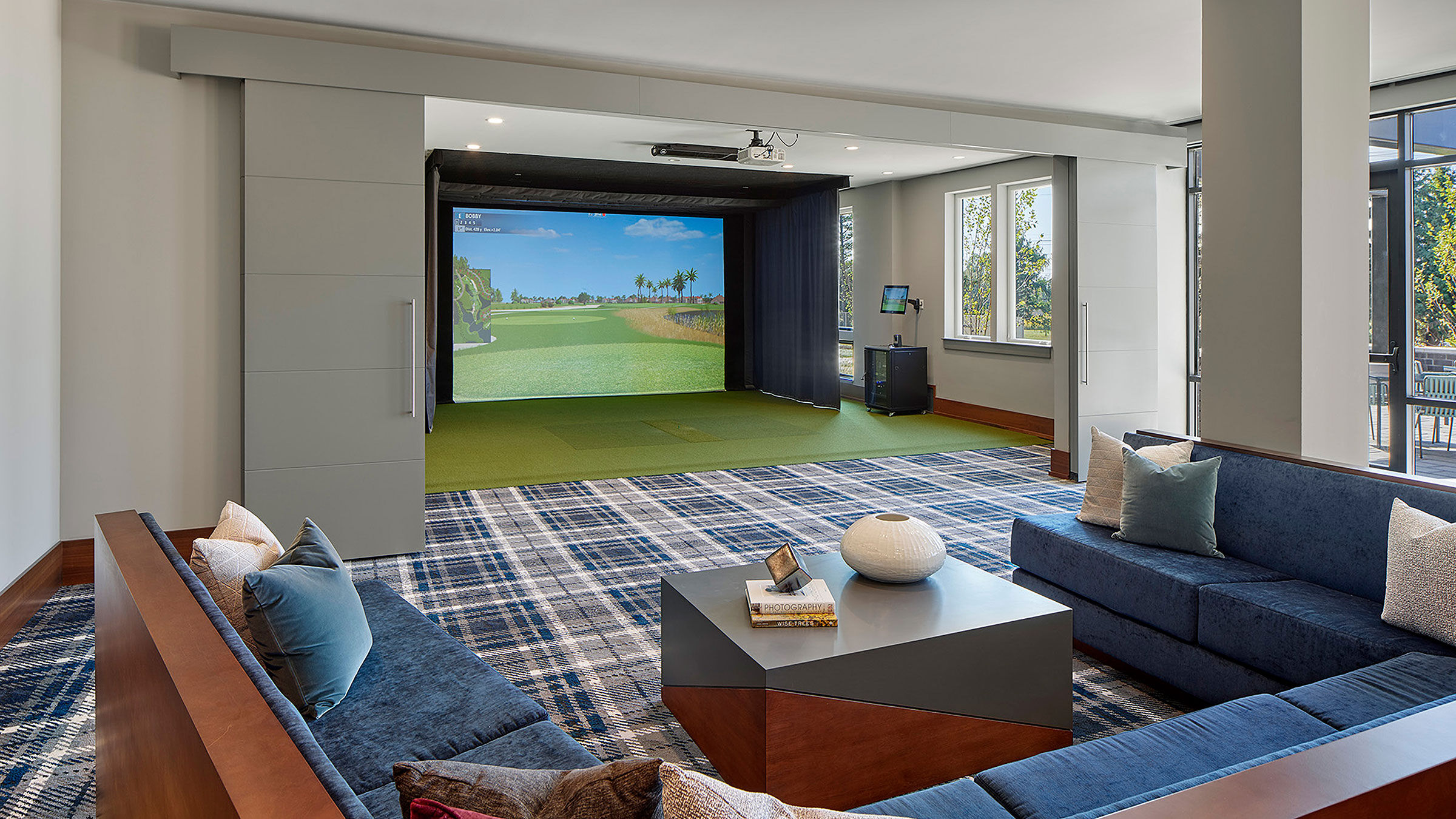 a room with a large screen and a golf course