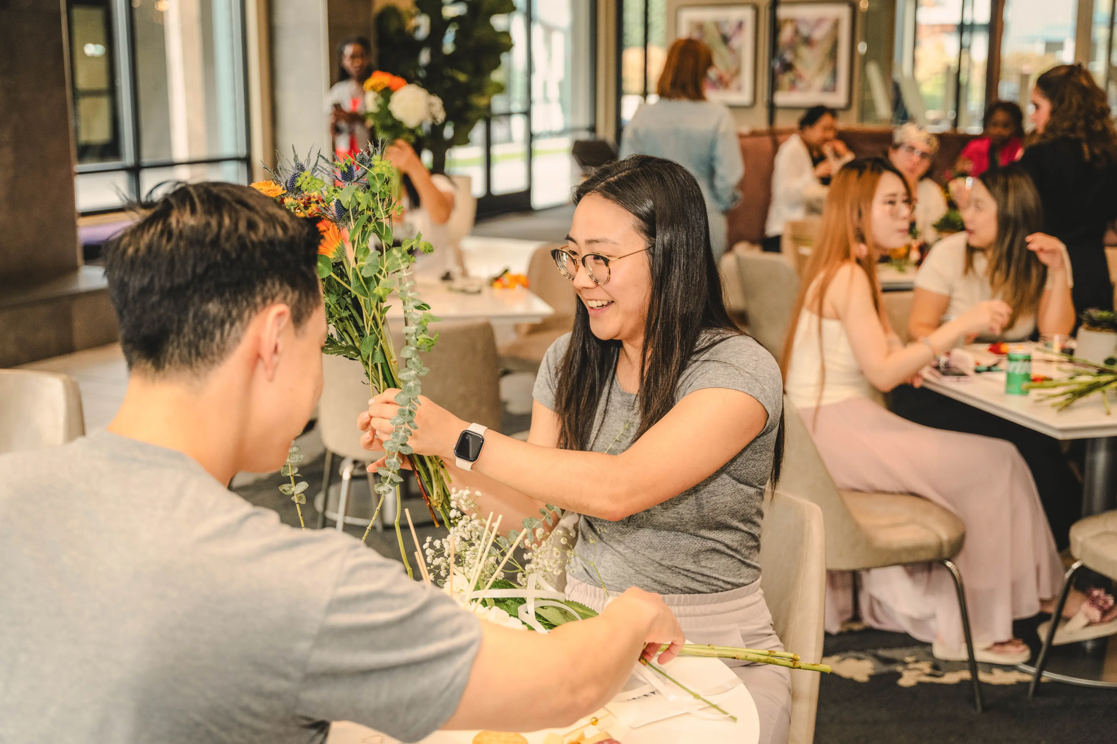 a man and woman sitting at tables with flowers