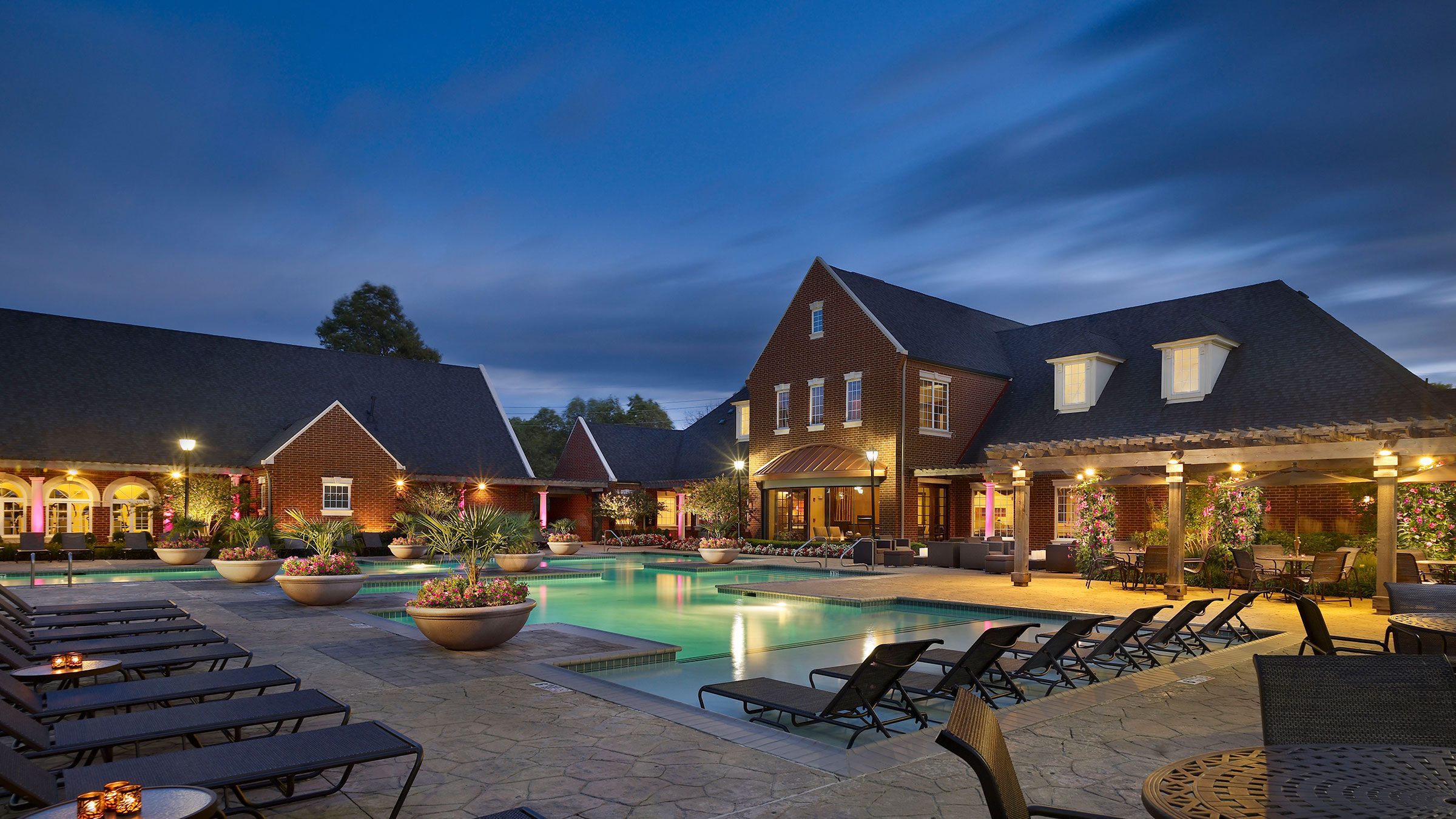 a pool and lounge chairs in front of a building