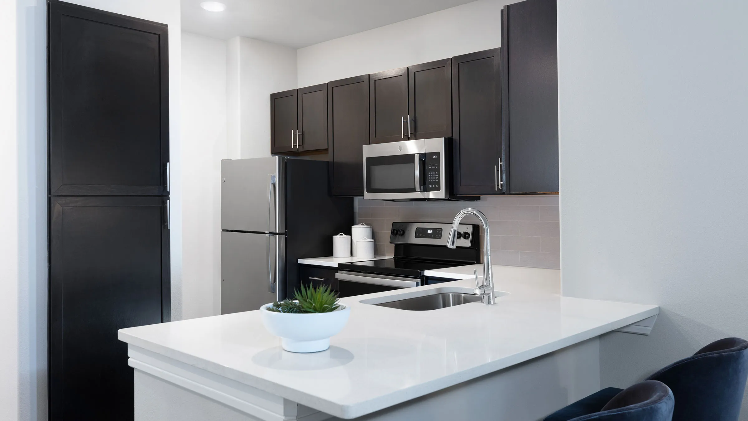 a kitchen with black cabinets and a white countertop