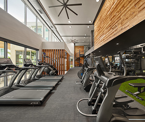 Fitness center with cardio equipment, green turf area with weights, and views to spiral staircase le