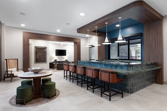 Bar Lounge area with bench and chair seating and large wood like doors and cabinets with green tile 