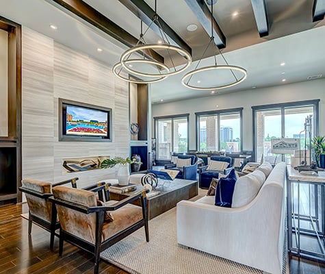 Las Colinas Lounge with blue and tan chairs, cream couch and tv in wall