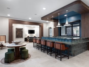 Bar Lounge area with bench and chair seating and large wood like doors and cabinets with green tile back splash