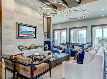 Lounge with cream sofa, blue and tan velvet chairs, tv in wall and views of courtyard behind