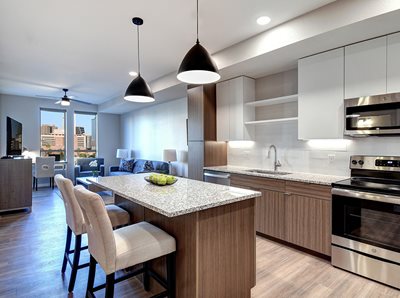 Kitchen with light wood cabinets, island with white quartz countertop and stainless steel appliances