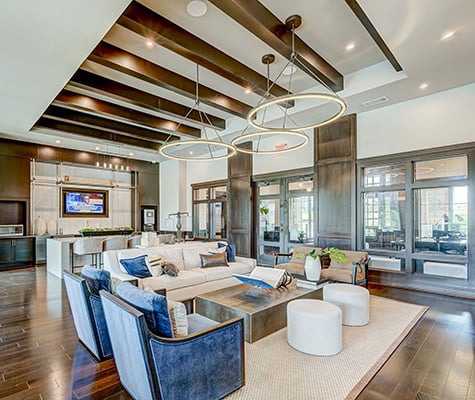 Las Colinas Lounge with blue chairs, cream sofa, tv in wall and island with bar seating