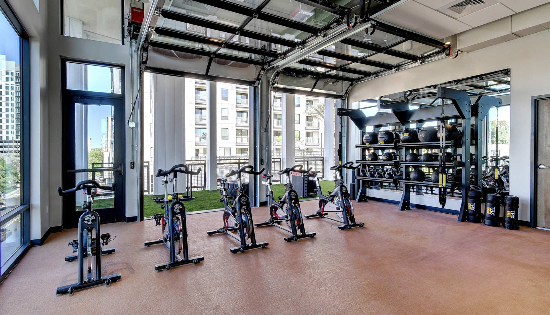 Spin studio with spin bikes, trx equipment, and access to outdoor workout area