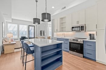 Kitchen with light wood cabinets, island with white quartz countertop and stainless steel appliances