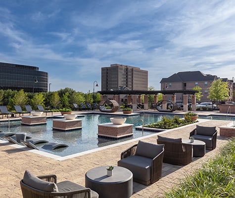 Las Colinas Pool with clubhouse in background, flower pot in foreground with white and pink flowers