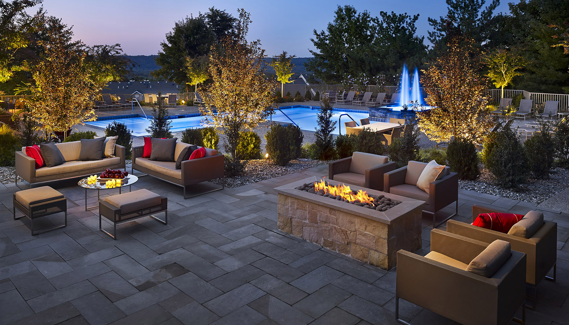 AVE Malvern's courtyard at dusk with exterior chairs, a firepit, and a pool