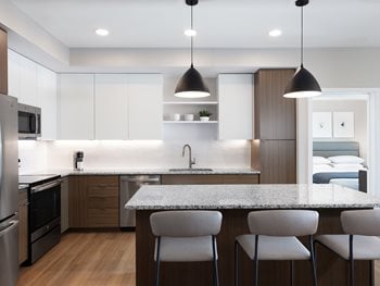 Kitchen with light wood cabinets, island with white quartz countertop and stainless steel appliances